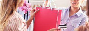 a woman holding a shopping bag and a credit card.